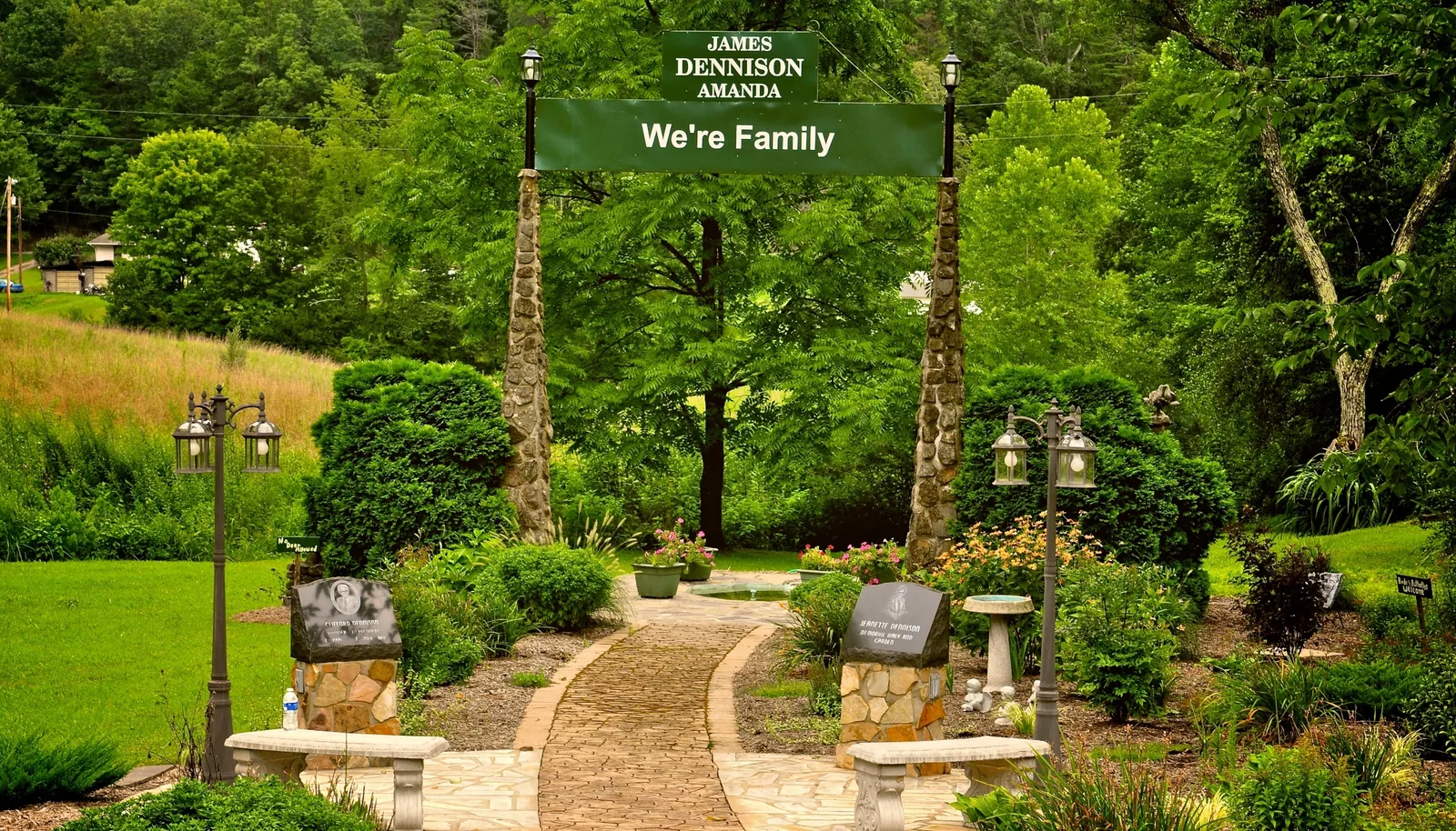 The We’re Family Park entrance, with the James and Amanda Dennison sign above a stone path through the gardens